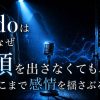 青い光が差し込む暗いクローゼットの中にマイクが立ち、匿名のシルエットと音波が広がる様子を背景に、「Adoはなぜ顔を出さなくても、ここまで感情を揺さぶるのか」と描かれたアイキャッチ画像